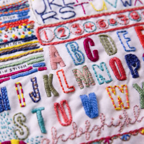 close-up of colorful embroidery - the schoolhouse sampler by Rebecca Ringquist featuring colorful alphabet letters and stitches