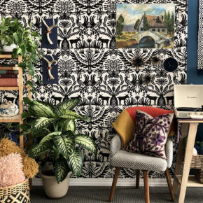 a colorful, textured set for a video that looks like an artist's studio with a black and white patterned wall hanging, wooden book shelves, plants, and chairs