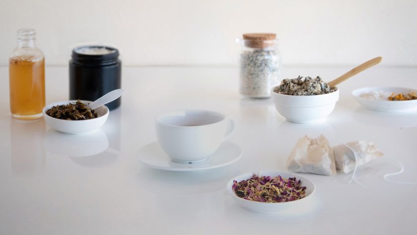 An elegant scattering of bowls and jars of dried botanicals and handmade candles and bath and body products