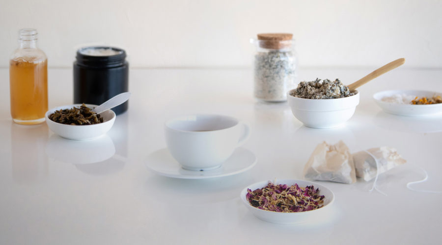 An elegant scattering of bowls and jars of dried botanicals and handmade candles and bath and body products