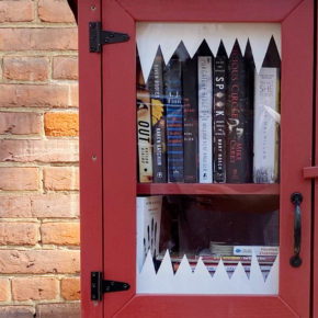 A free library box filled with spooky books and decorated with monster teeth for Halloween