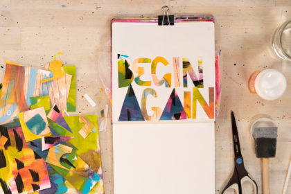 An open sketchbook by abstract painter Abby Houston with painted text that reads "Begin Again"