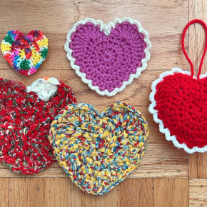 several crocheted hearts in different colors on a wood background