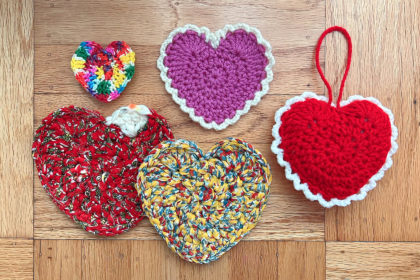 several crocheted hearts in different colors on a wood background