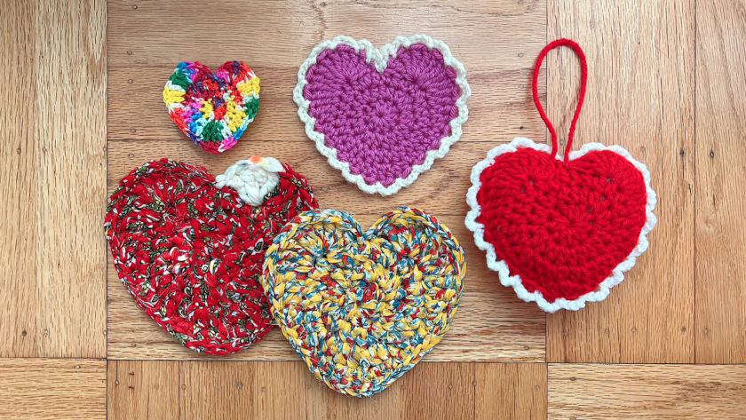 several crocheted hearts in different colors on a wood background