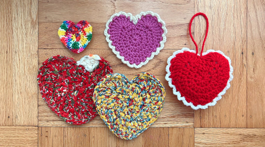 several crocheted hearts in different colors on a wood background