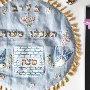 image of a light blue, handmade matzah cover with gold tassel trim