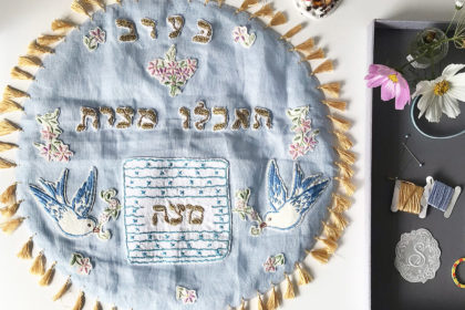image of a light blue, handmade matzah cover with gold tassel trim