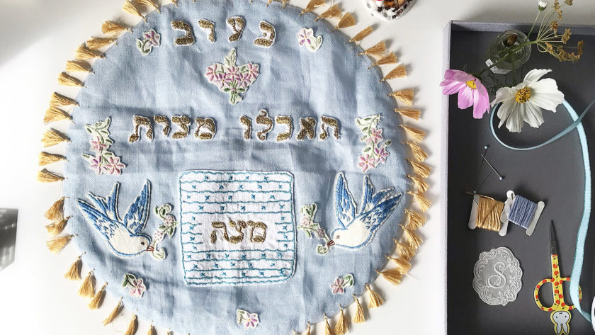 image of a light blue, handmade matzah cover with gold tassel trim