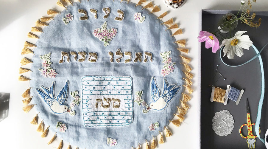 image of a light blue, handmade matzah cover with gold tassel trim