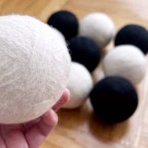 image of several black and white wool felted dryer balls and one being held in a hand