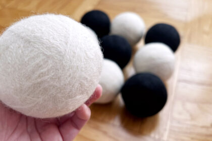 image of several black and white wool felted dryer balls and one being held in a hand