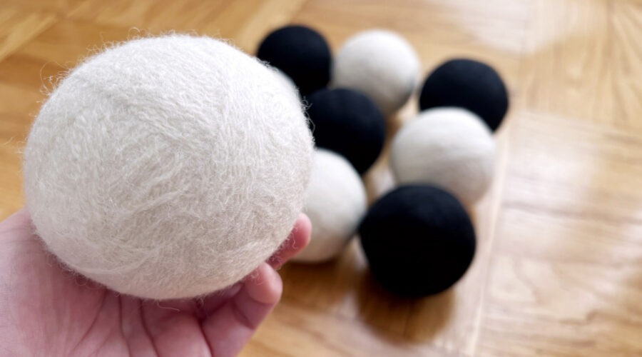 image of several black and white wool felted dryer balls and one being held in a hand