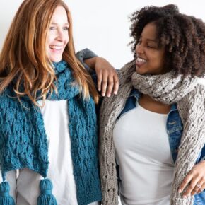 image of 2 women standing next to each other wearing handmade knitted scarves and smiling