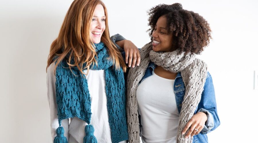 image of 2 women standing next to each other wearing handmade knitted scarves and smiling