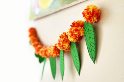 image of torana or garland made of yarn pom poms and craft foram leaves to represent marigolds and mango leaves for Diwali
