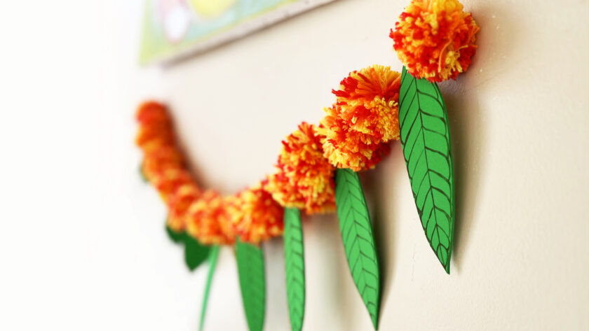 image of torana or garland made of yarn pom poms and craft foram leaves to represent marigolds and mango leaves for Diwali