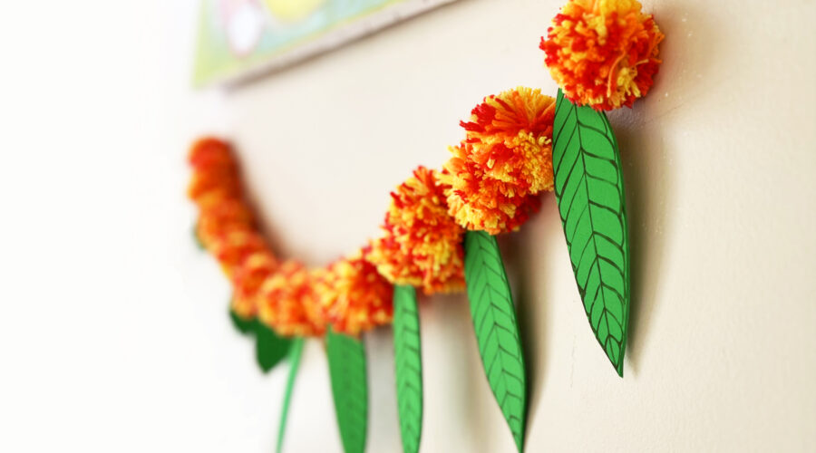 image of torana or garland made of yarn pom poms and craft foram leaves to represent marigolds and mango leaves for Diwali