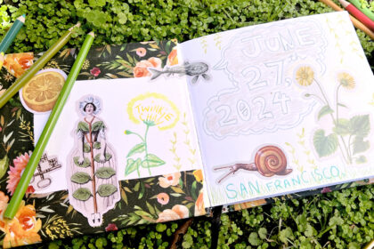image of an open sketchbook on a bed of moss, pages revealing nature-inspired stickers and pencil drawings of flowers, snails, and strange creatures, plus colored pencils