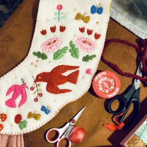 image of a handmade heirloom stocking in off-white felt with colorful appliques of birds and flowers