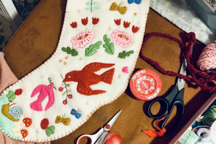 image of a handmade heirloom stocking in off-white felt with colorful appliques of birds and flowers