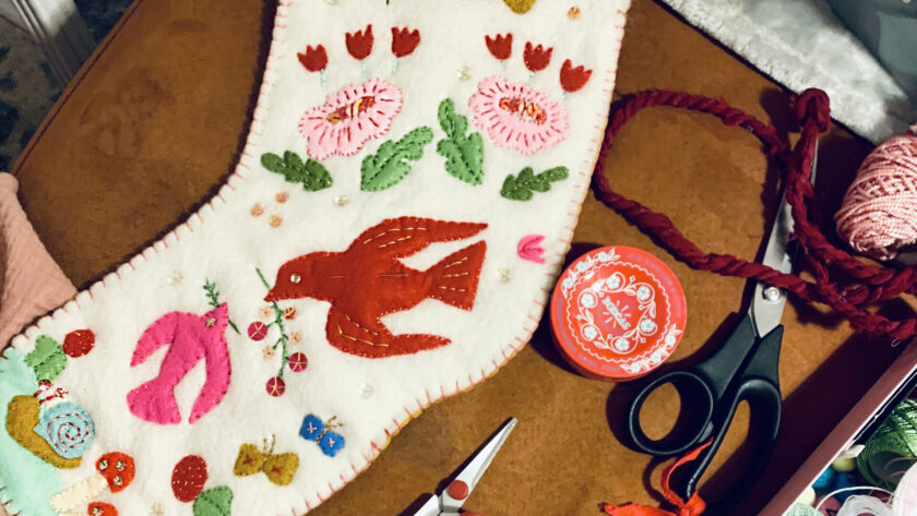 image of a handmade heirloom stocking in off-white felt with colorful appliques of birds and flowers