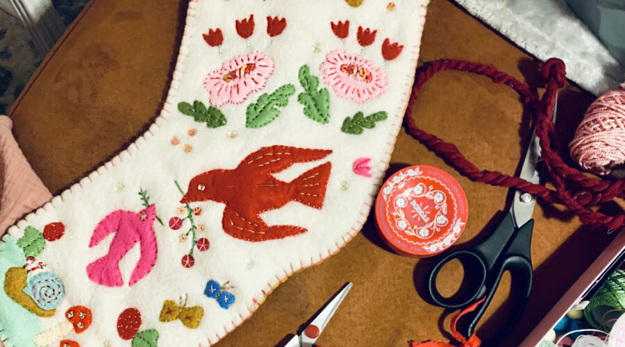 image of a handmade heirloom stocking in off-white felt with colorful appliques of birds and flowers