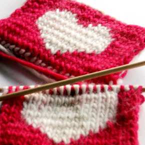 close up image of red knitted coasters with a white heart in the middle