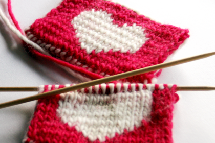 close up image of red knitted coasters with a white heart in the middle