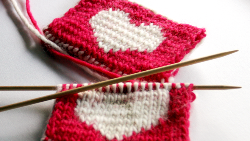 close up image of red knitted coasters with a white heart in the middle